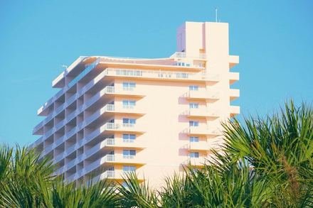 Sample listing: a pink and white oceanfront condo building behind palm trees